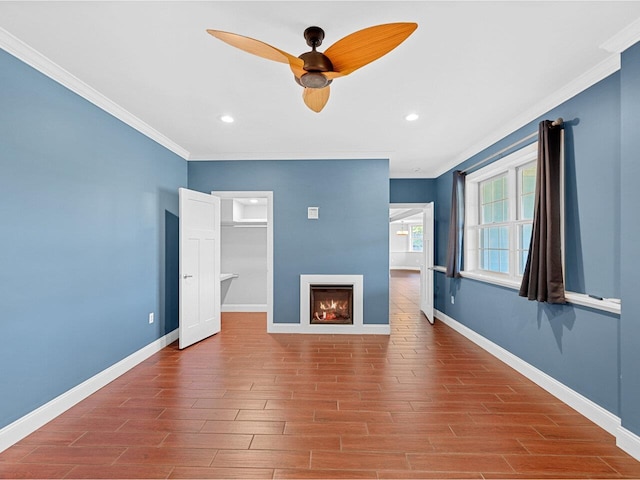 unfurnished living room with a warm lit fireplace, ornamental molding, wood finished floors, and baseboards