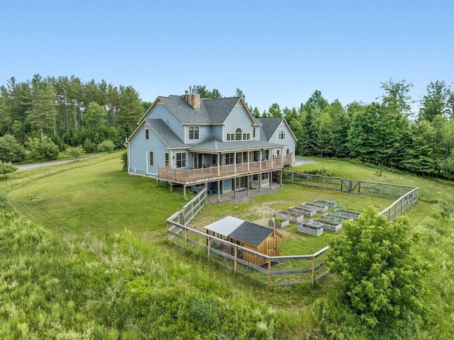 back of house featuring a garden, a chimney, and a yard