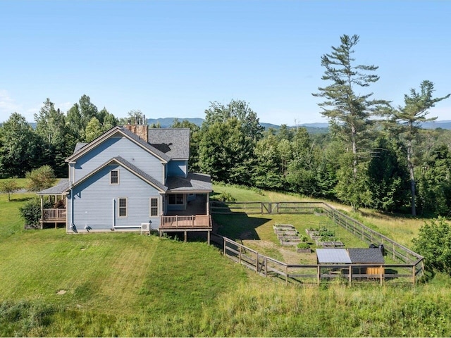 back of property with a chimney, fence, a deck, and a yard