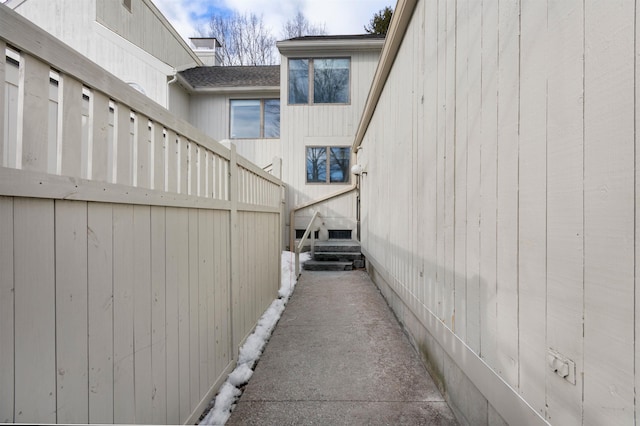 view of side of property featuring a shingled roof and fence