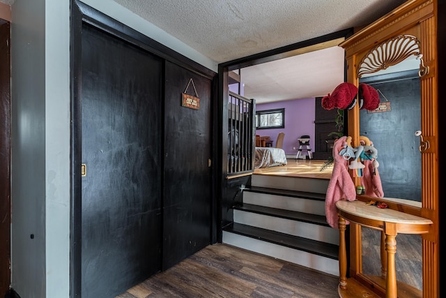 staircase with a textured ceiling and wood finished floors