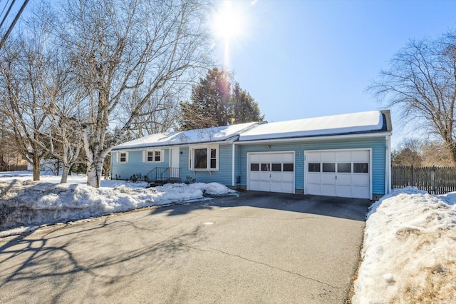 ranch-style house with a garage, driveway, and fence