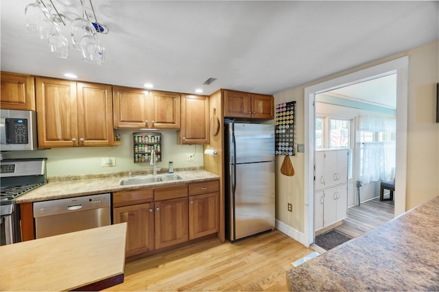 kitchen featuring light wood-type flooring, a sink, stainless steel appliances, light countertops, and brown cabinets