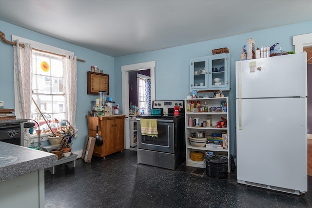 kitchen featuring stainless steel electric range, glass insert cabinets, a wealth of natural light, and freestanding refrigerator