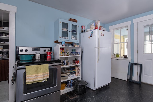 kitchen featuring stainless steel range with electric stovetop, freestanding refrigerator, and glass insert cabinets