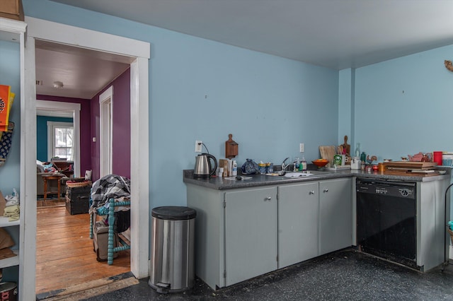 kitchen with dark countertops, black dishwasher, and a sink