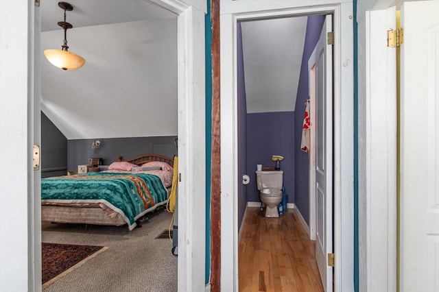 bedroom with vaulted ceiling, wood finished floors, and baseboards