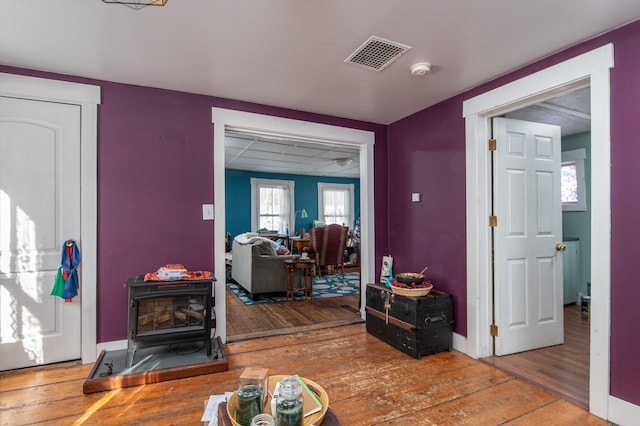 interior space with visible vents, hardwood / wood-style flooring, a wood stove, and baseboards