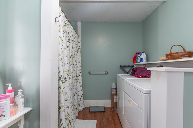 laundry area with laundry area, washing machine and dryer, wood finished floors, and baseboards