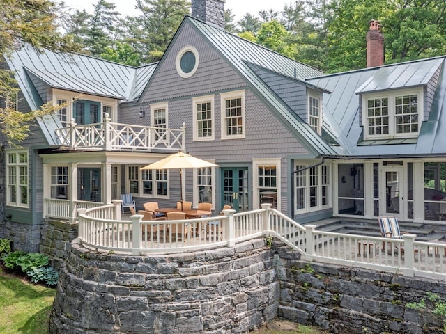 back of house with a standing seam roof, a patio area, a chimney, and metal roof