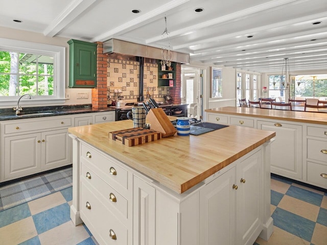 kitchen featuring butcher block counters, a sink, white cabinetry, beam ceiling, and light floors