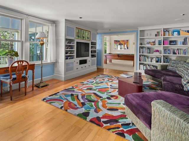 living room with ornamental molding, built in features, baseboards, and wood finished floors