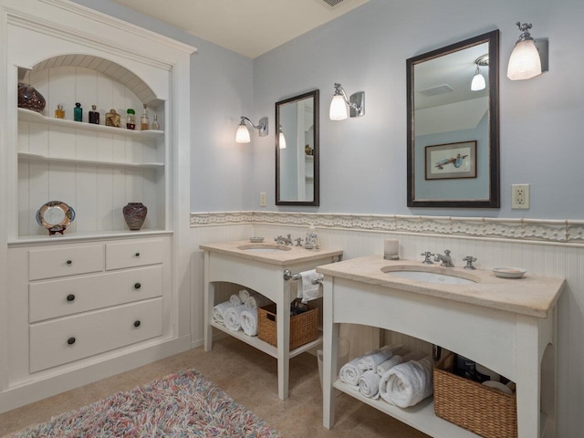 bathroom with two vanities, a sink, and wainscoting