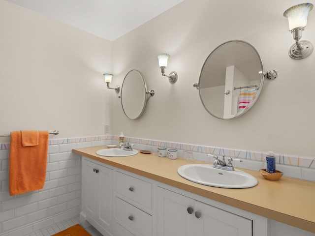 full bath featuring a sink, tile walls, and double vanity