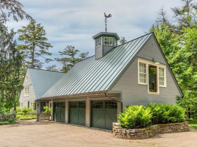 view of home's exterior featuring a standing seam roof, dirt driveway, and metal roof