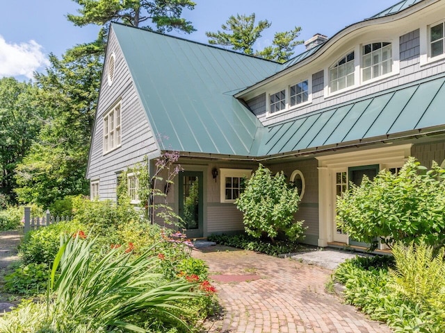 view of front facade with a standing seam roof, metal roof, and a chimney