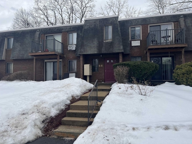 multi unit property with brick siding, mansard roof, and a balcony