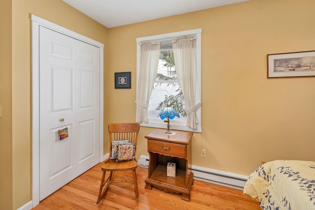 bedroom featuring baseboards, a baseboard heating unit, baseboard heating, and wood finished floors