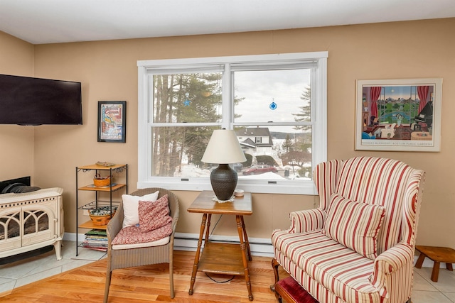 sitting room with a baseboard heating unit, wood finished floors, and baseboards