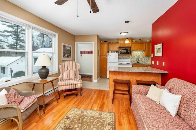 kitchen featuring brown cabinets, hanging light fixtures, light wood-type flooring, white appliances, and a peninsula