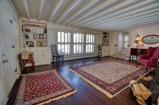 living area with built in features, arched walkways, wood finished floors, a baseboard heating unit, and beam ceiling