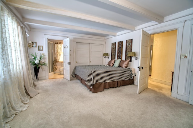 carpeted bedroom featuring connected bathroom and beam ceiling