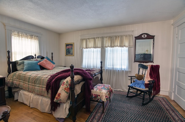 bedroom with multiple windows, a textured ceiling, and wood finished floors