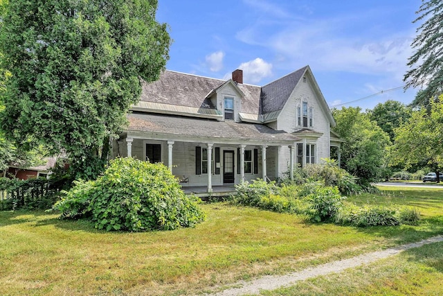 rear view of house featuring covered porch, a lawn, and a chimney