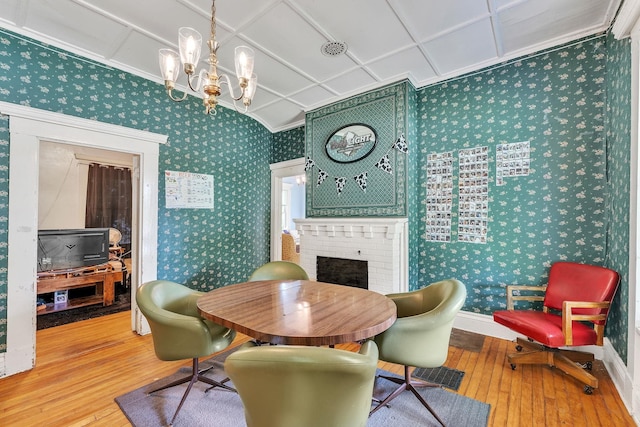 dining room featuring wallpapered walls, a fireplace, a chandelier, and hardwood / wood-style flooring