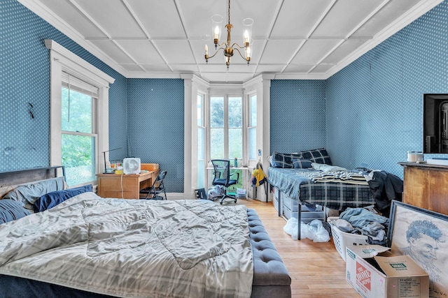 bedroom with ornamental molding, wood finished floors, a notable chandelier, and wallpapered walls