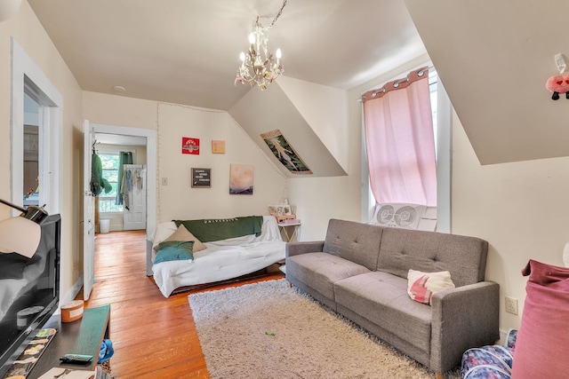 living area featuring lofted ceiling, light wood-style flooring, and a chandelier