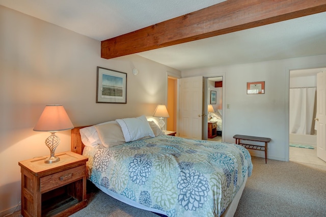 carpeted bedroom with beamed ceiling, ensuite bath, and baseboards