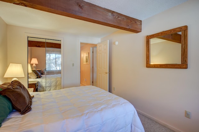 carpeted bedroom with a textured ceiling, a closet, beam ceiling, and baseboards