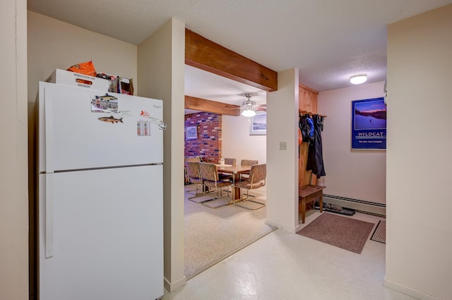 kitchen with a baseboard radiator, beamed ceiling, a textured ceiling, and freestanding refrigerator