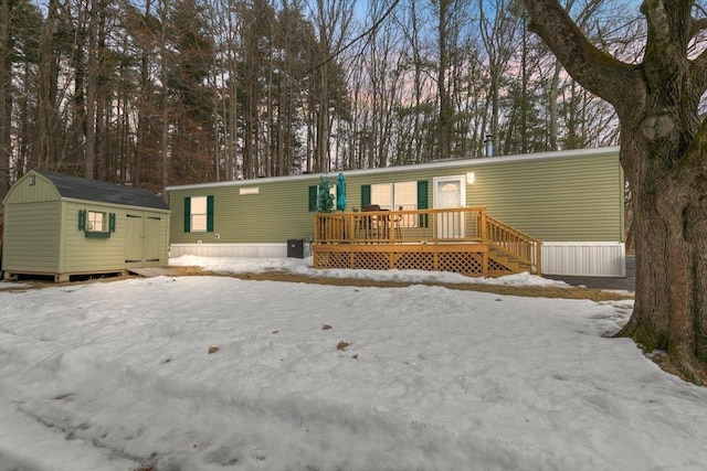 snow covered back of property with a shed and an outdoor structure