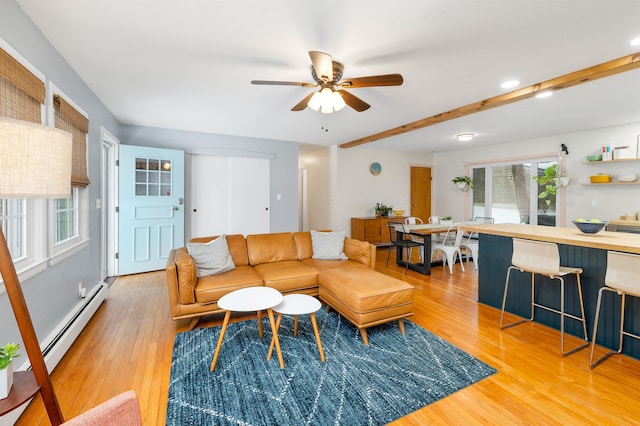 living room with a baseboard heating unit, ceiling fan, and light wood-type flooring