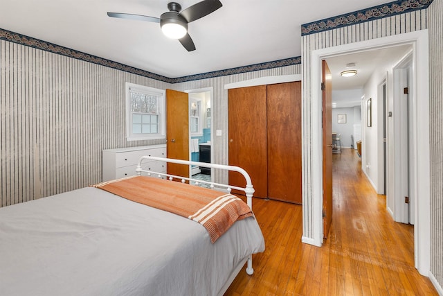 bedroom with ceiling fan, light wood-style floors, a closet, and wallpapered walls