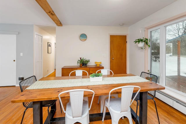 dining room with beam ceiling, a baseboard radiator, and light wood-style flooring