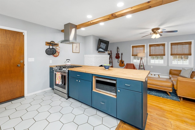 kitchen featuring appliances with stainless steel finishes, butcher block countertops, island exhaust hood, and blue cabinets