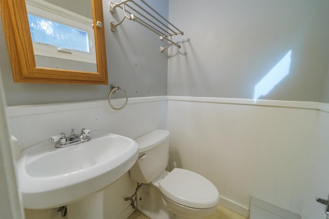 half bathroom featuring a wainscoted wall, a sink, and toilet