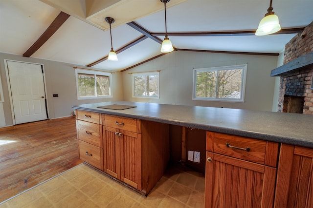 kitchen with brown cabinetry, vaulted ceiling with beams, light wood-type flooring, a fireplace, and pendant lighting