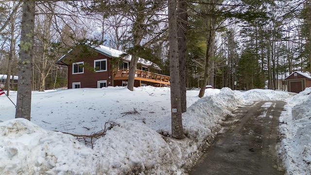 yard layered in snow featuring a garage and a wooden deck