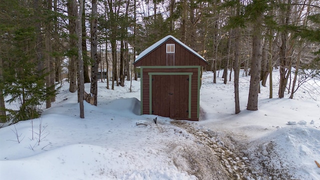 snow covered structure featuring a storage unit and an outbuilding