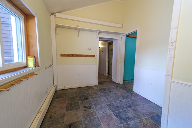 hall featuring lofted ceiling, stone finish floor, wainscoting, and a baseboard radiator