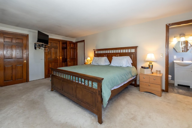 bedroom featuring a sink, connected bathroom, and light colored carpet