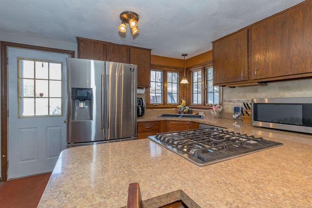 kitchen with a sink, light countertops, appliances with stainless steel finishes, backsplash, and brown cabinets