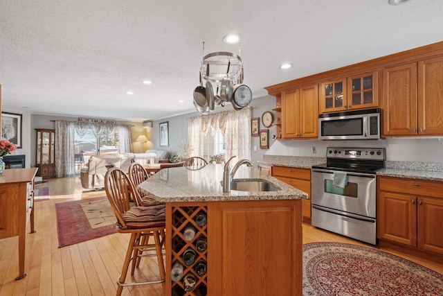 kitchen featuring brown cabinets, stainless steel appliances, open floor plan, a sink, and plenty of natural light