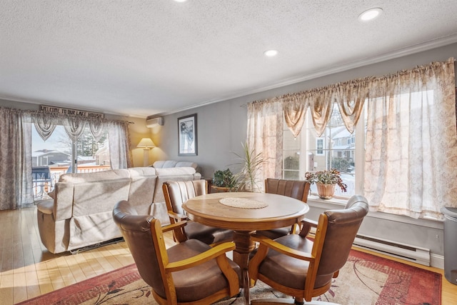 dining space featuring ornamental molding, wood finished floors, baseboard heating, a textured ceiling, and recessed lighting