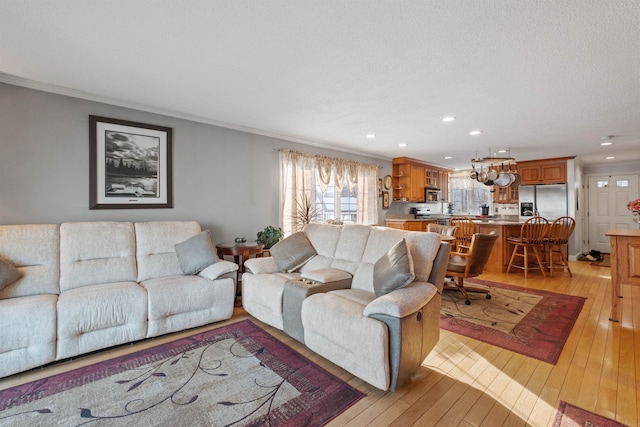 living area with light wood-style floors, ornamental molding, and recessed lighting