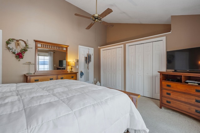 carpeted bedroom with lofted ceiling, a ceiling fan, and multiple closets